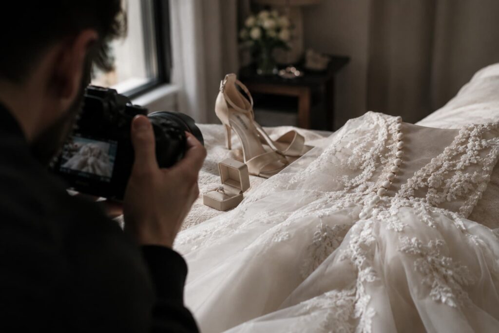 Fotógrafo profesional fotografiando el vestido de novia, zapatillas y anillo de compromiso sobre la cama durante el getting ready en CDMX.