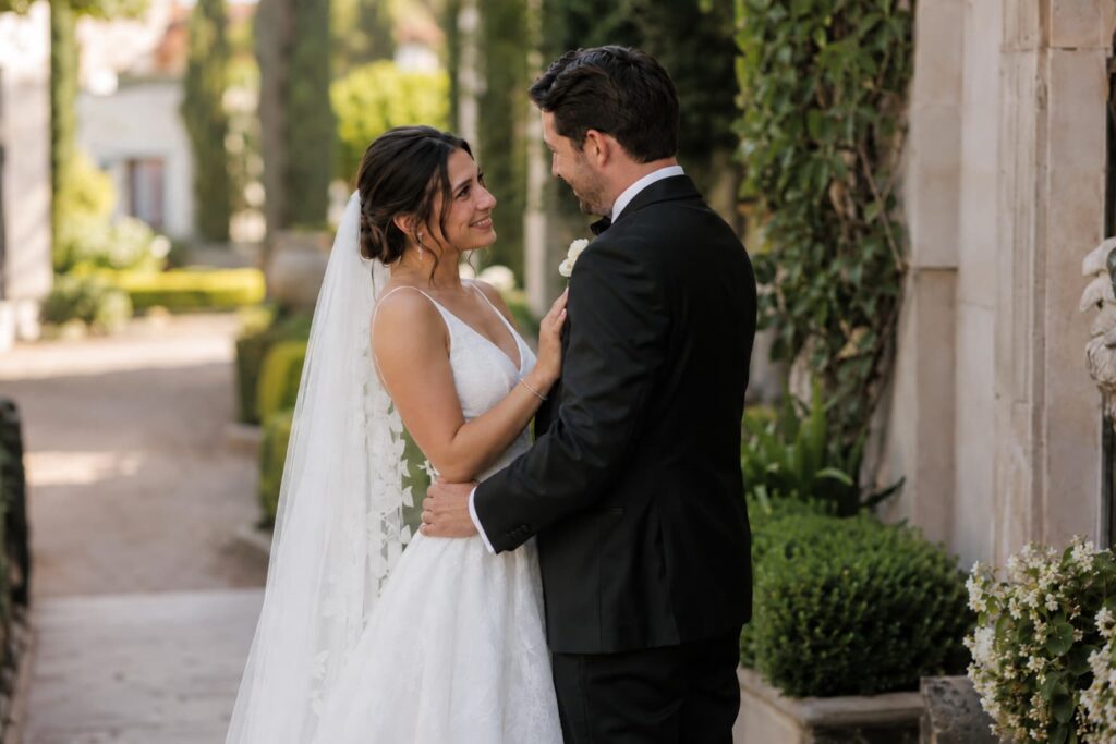 Novios abrazados mirándose fijamente con amor durante su sesión de retratos de pareja preboda en un jardín