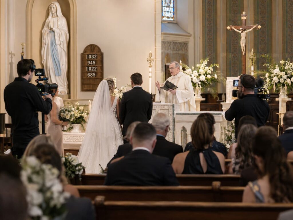 Dos videógrafos grabando la ceremonia religiosa de una boda en iglesia desde distintas perspectivas.